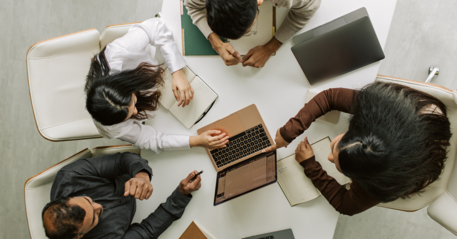 A diverse group collaborating around a laptop discussing modern job search strategies during a team meeting.