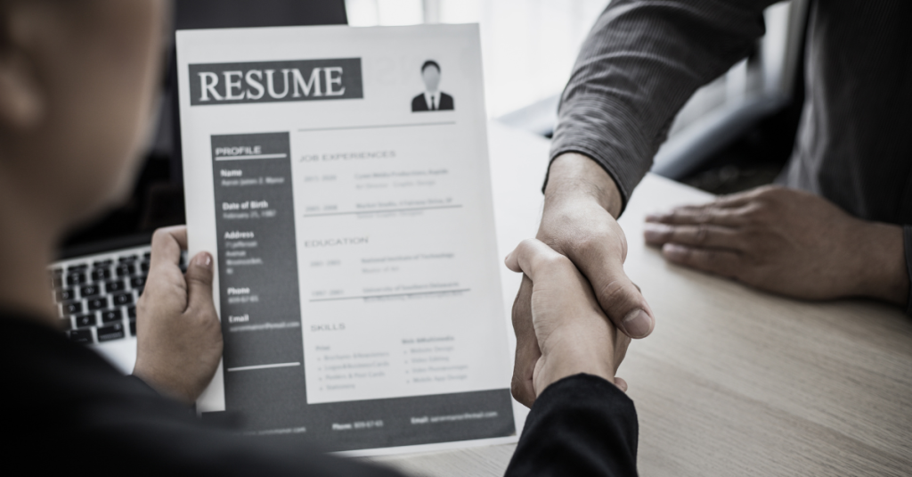 Job candidate handing resume to recruiter, how ATS applicant tracking system affects resume success during hiring.